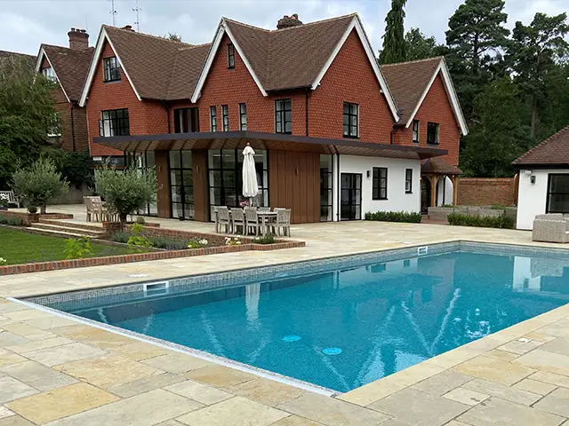 A heated home outdoor swimming pool with a large patio area.