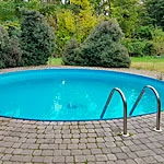 An circular outside plunge pool with a small brick paving surround.