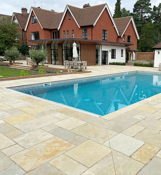 Outdoor swimming pool with house in background and patio surround