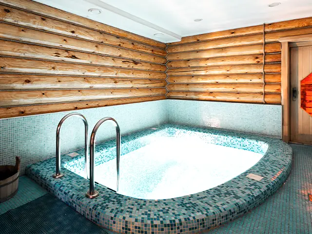 A brightly lit basement plunge pool next to a sauna.